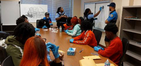 high school students in a workshop with the New Orleans Police Department learning about criminal justice